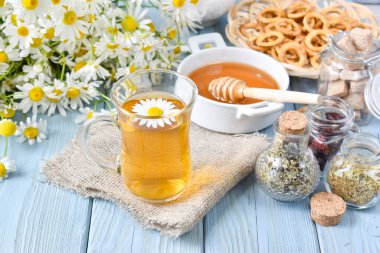 Tahta bir masada şeffaf bir fincanda papatya çayı.