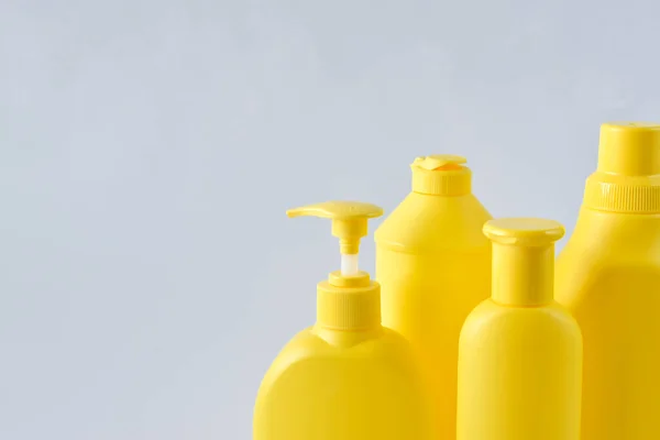 Four yellow plastic bottles on a white background on the right side — Stock Photo, Image