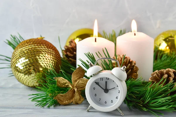 Christmas composition. Two candles and pine branches with cones and a white alarm clock. — Stock Photo, Image
