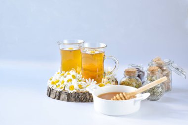 Kurumuş ve taze otlar, çiçekler, tıbbi çay ve bal açık mavi arka planda.