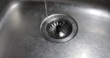 Waschbecken mit Abflluss fliet ein schmaler Wasserstrahl