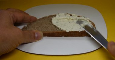 Bıçaklı el peynirli sandviç sürer.