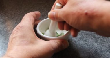 Porselen bir havanda bitkilerin parçaları ginko yaprakları gibi ezilir.