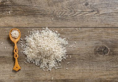 Basmati Pirinç kazık tahta kaşıkla üstten görünüm antika ahşap arka plan üzerinde. 