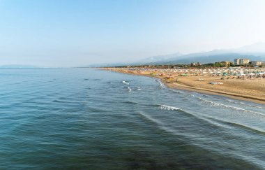 Versilia, Toskana, İtalya 'da sabahın erken saatlerinde Marina di Pietrasanta plajı beyaz kum, şemsiye ve sandalye manzarası
