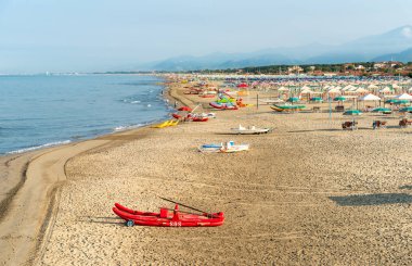 Versilia, Toskana, İtalya 'da sabahın erken saatlerinde Marina di Pietrasanta plajı beyaz kum, şemsiye ve sandalye manzarası