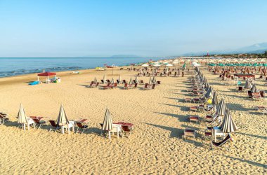 Versilia, Toskana, İtalya 'da sabahın erken saatlerinde Marina di Pietrasanta plajı beyaz kum, şemsiye ve sandalye manzarası