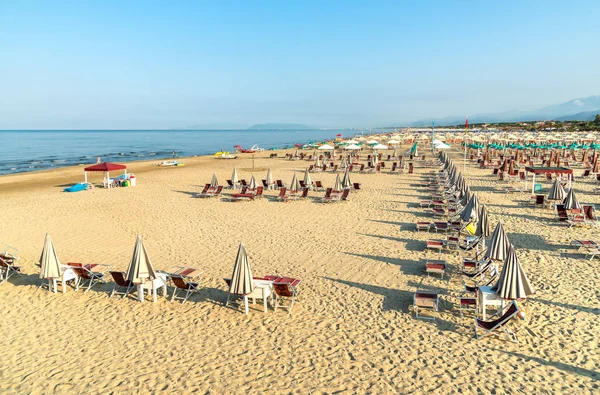 Versilia, Toskana, İtalya 'da sabahın erken saatlerinde Marina di Pietrasanta plajı beyaz kum, şemsiye ve sandalye manzarası