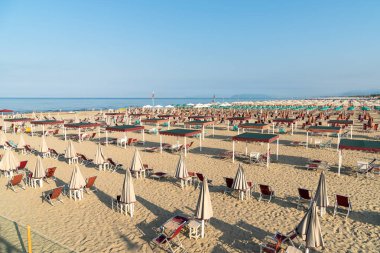 Versilia, Toskana, İtalya 'da sabahın erken saatlerinde Marina di Pietrasanta plajı beyaz kum, şemsiye ve sandalye manzarası