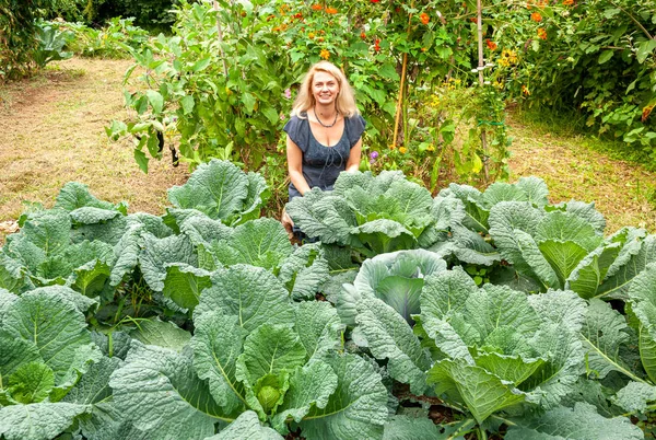 Smiling woman in the vegetable garden savoy cabbage.