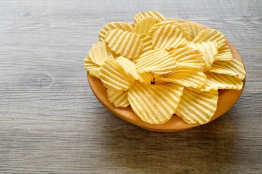 Köhne ahşap masadaki ahşap bir kasede oyulmuş altın patates cipsi..