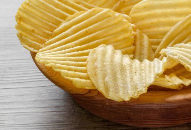 Köhne ahşap masadaki ahşap bir kasede oyulmuş altın patates cipsi..
