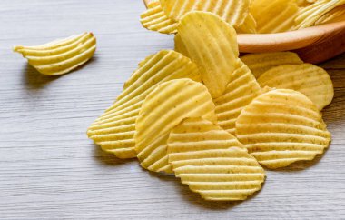 Köhne ahşap masadaki ahşap bir kasede oyulmuş altın patates cipsi..