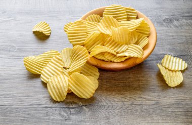 Köhne ahşap masadaki ahşap bir kasede oyulmuş altın patates cipsi..