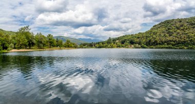 Ghirla Gölü 'nün panoraması bir yaz günü bulutların ve ağaçların yansımasıyla, Valganna, Varese, İtalya