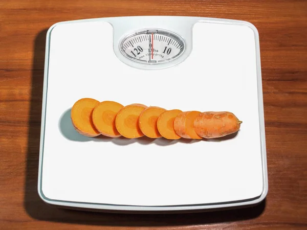 인간의 무게를 측정 하는 저울에 썬된 당근 — 스톡 사진