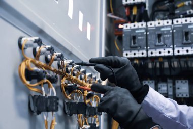 Elektrik mühendisi, ana güç dağıtım panosundaki elektrik akımı voltajını kontrol etmek için dijital çoklu metre ölçüm ekipmanı kullanıyor..