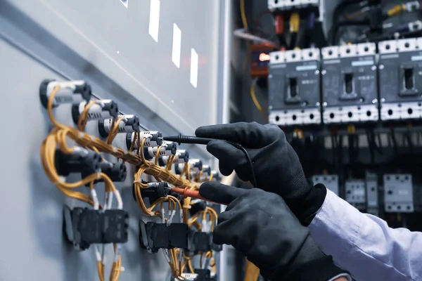 Elektrik mühendisi, ana güç dağıtım panosundaki elektrik akımı voltajını kontrol etmek için dijital çoklu metre ölçüm ekipmanı kullanıyor..