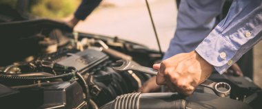 Araba motorunu tamir etmek için ingiliz anahtarı kullanan tamirci ellerini kapat. Araba sigortası desteği ve hizmetleri kavramları.