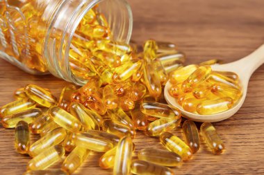 Tahta kaşıkta morina yağı kapsülü yığını. Sağlık hizmetleri kavramları için beslenme desteği.