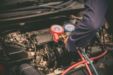 Otomobil tamircisi araba klimalarını doldurmak için ölçüm aleti kullanıyor. Araba bakım ve sigorta hizmetleri kavramları.