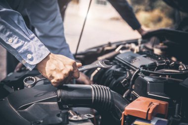 Araba motorunu tamir etmek için İngiliz anahtarını kullanan oto tamirci elleri. Araba bakımı onarım ve sigorta hizmetleri kavramları.
