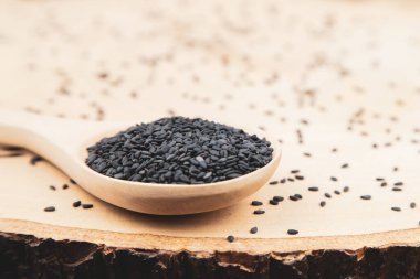 Sağlıklı yemek ve diyet kavramları için tahta kaşıkta siyah susam tohumları..