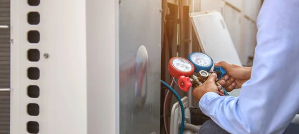 Hava onarım teknisyeni endüstriyel fabrika klimalarını doldurmak ve dış hava kompresörü ünitesini kontrol etmek için ölçüm ekipmanı kullanıyor..