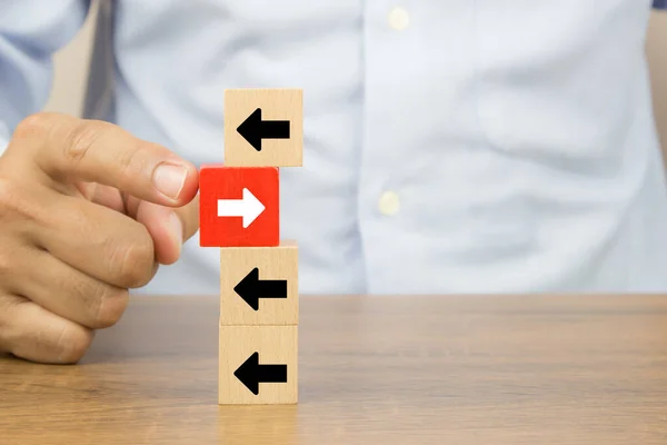 商界人士亲手选择带有箭头头图标的立方体木制玩具博客 为企业变革领导者指明了与增长和成功理念相反的方向 — 图库照片