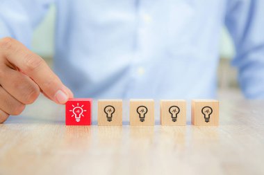 Özenle seçilmiş küp şeklindeki tahta blokların yakın plan görüntüsü. Ampul sembolü, yaratıcılık ve yenilik fikirlerini üst üste yığmış..