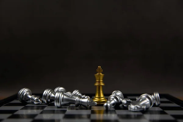 The golden chess king stands in the middle of the falling silver chess. Concepts of leadership and business strategy plans.