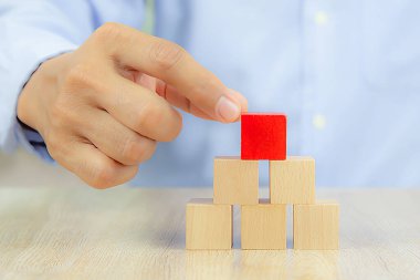 Yakın plan el, iş tasarımı konsepti için grafiksiz istiflenmiş bir küp şeklinde tahta blok oyuncağı ve çocuk vakfı uygulama becerileri için etkinlik seçin.