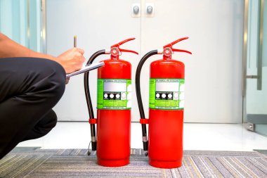 Fire fighter are checking fire extinguishers tank in the building concepts of fire prevention emergency safety rescue of fire services and training clipart