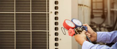 Manifold göstergesi kullanan teknisyen endüstriyel fabrika klimalarını doldurmak ve dış hava kompresör ünitesini kontrol etmek için ekipman ölçüyor..