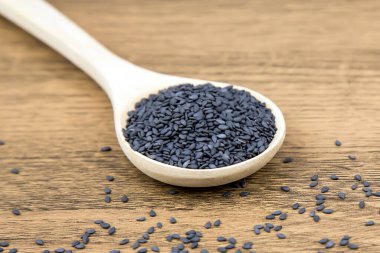 Sağlıklı yemek ve diyet kavramları için tahta kaşıkta siyah susam tohumları..