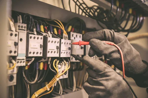 Elektrik mühendisi ana güç dağıtım panosundaki elektrik akımı voltajını kontrol etmek için dijital çoklu metre ölçüm ekipmanı kullanıyor..
