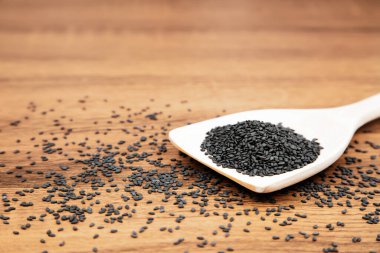 Sağlıklı yemek ve diyet kavramları için tahta kaşıkta siyah susam tohumları..