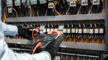 Elektrik mühendisi ana güç dağıtım panosundaki elektrik akımı voltajını kontrol etmek için dijital çoklu metre ölçüm ekipmanı kullanıyor..