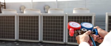 Manifold göstergesi kullanan teknisyen endüstriyel fabrika klimalarını doldurmak ve dış hava kompresör ünitesini kontrol etmek için ekipman ölçüyor..