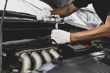 Otomobil tamircisinin araba motorunu tamir etmek için ingiliz anahtarını kullanması. Araba bakımı onarım ve sigorta hizmetleri kavramları.