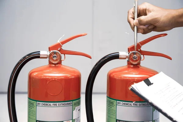 Fire fighter are checking red fire extinguishers tank in the building concepts of fire prevention emergency and safety rescue of fire services and training.