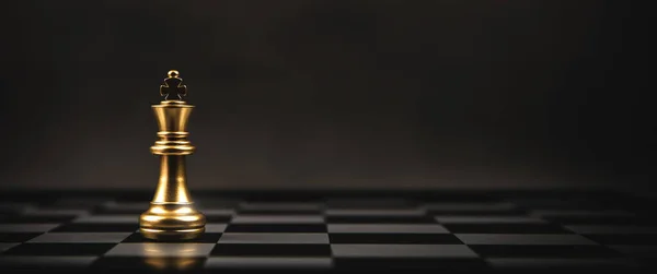 Satranç tahtası üzerinde duran Satranç Kralı stratejik plan ve profesyonel organizasyon yönetim lideri.