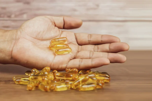 Hand choose a cod liver oil capsule from a pile of cod liver oil or fish oil dietary supplement for health-care concepts.