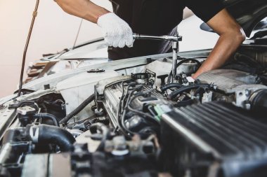 Otomobil tamircisinin araba motorunu tamir etmek için ingiliz anahtarını kullanması. Araba bakımı onarım ve sigorta hizmetleri kavramları.