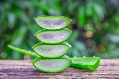 Sağlıklı ürünler için ahşap masa üzerindeki taze aloe vera yaprakları ve dilimler.
