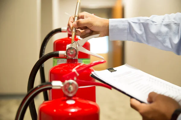 Feuerwehrmann Überprüft Manometer Eines Roten Feuerlöschtanks Gebäude — Stockfoto