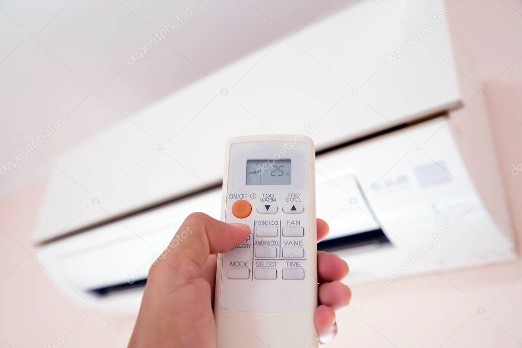 Remote control in hand closeup,Presses the button on the remote control switch to set air conditioner's temperature