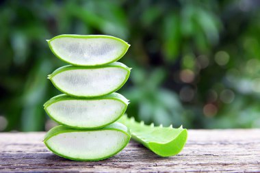 Sağlıklı ürünler için ahşap masa üzerindeki taze aloe vera yaprakları ve dilimler.