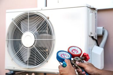 Manifold göstergesi kullanan teknisyen endüstriyel fabrika klimalarını doldurmak ve dış hava kompresör ünitesini kontrol etmek için ekipman ölçüyor..