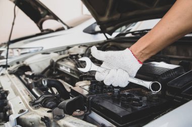 Otomobil tamircisinin araba motorunu tamir etmek için ingiliz anahtarını kullanması. Araba bakımı onarım ve sigorta hizmetleri kavramları.